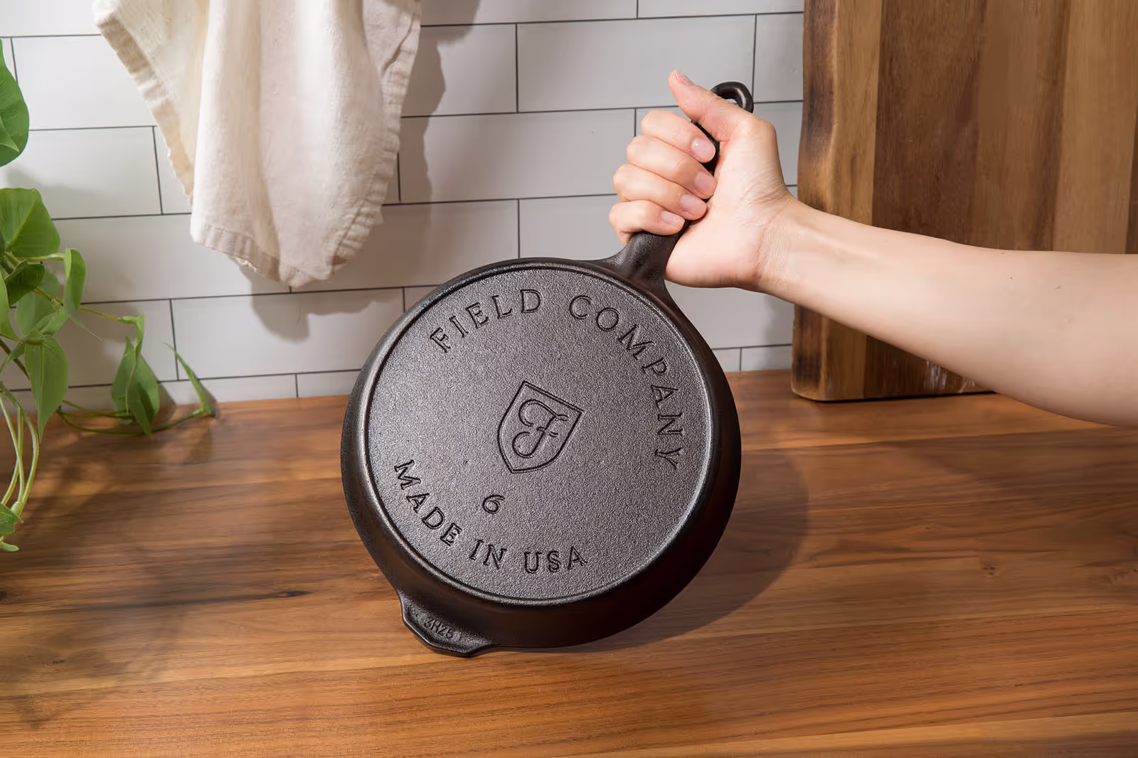a hand model holding a cast iron pan